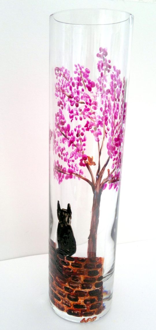 Bud vase with a Spring tree with pinkblossom and a black cat on a wall