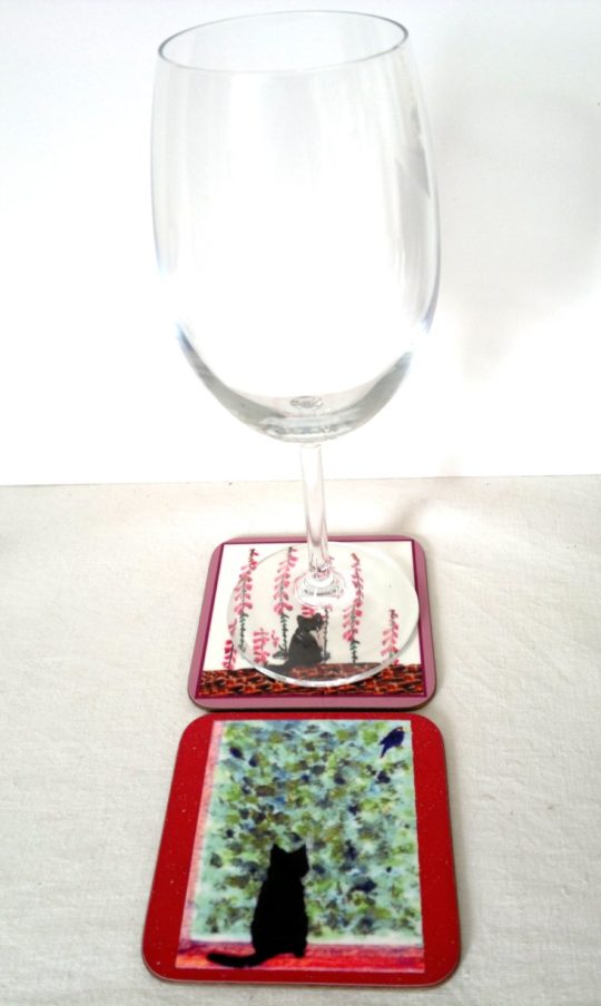 Photo of two coasters with cats in a garden and a wine glass