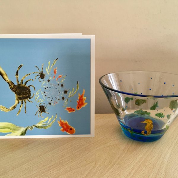 A card with an abstract rock pool with crabs and fish. Photographed with a bowl hand painted with fish